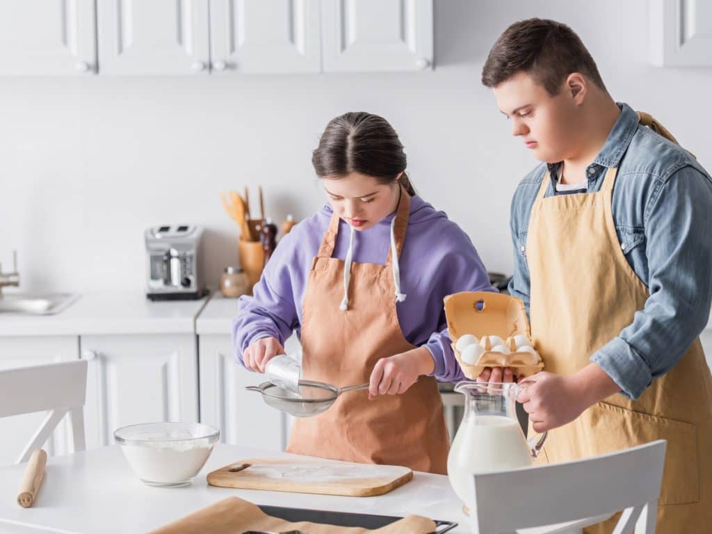 Teenagers,With,Down,Syndrome,Cooking,Near,Milk,And,Flour,In